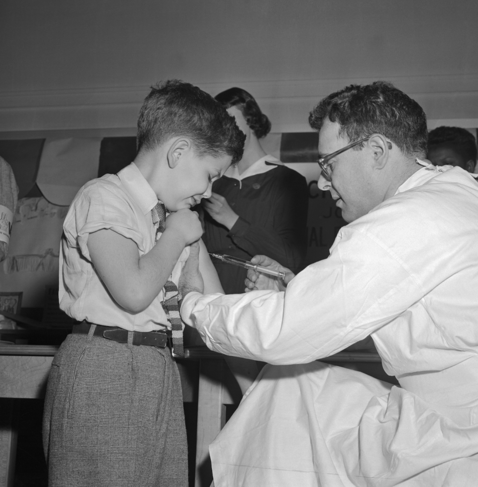 A young boy receives a polio vaccine from a healthcare professional in a clinic setting