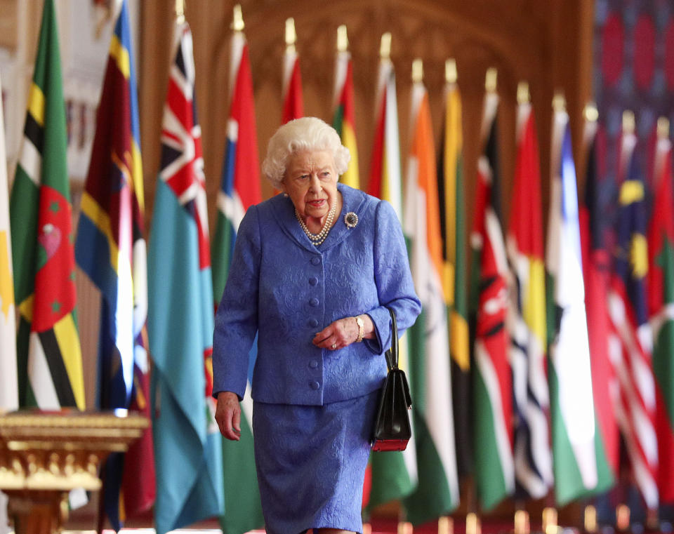 WINDSOR, UNITED KINGDOM:  In this undated image released on March 6, 2021, Queen Elizabeth II walks past Commonwealth flags in St George's Hall at Windsor Castle, to mark Commonwealth Day, in Windsor, England.  (Photo by Steve Parsons - WPA Pool/Getty Images)