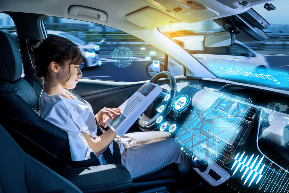 A woman reads a book while sitting in a driverless car.