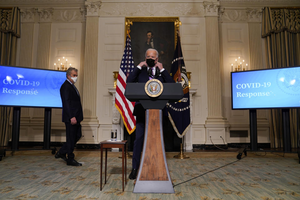 President Joe Biden removes his face mask before delivering remarks on COVID-19, in the State Dining Room of the White House, Tuesday, Jan. 26, 2021, in Washington. (AP Photo/Evan Vucci)