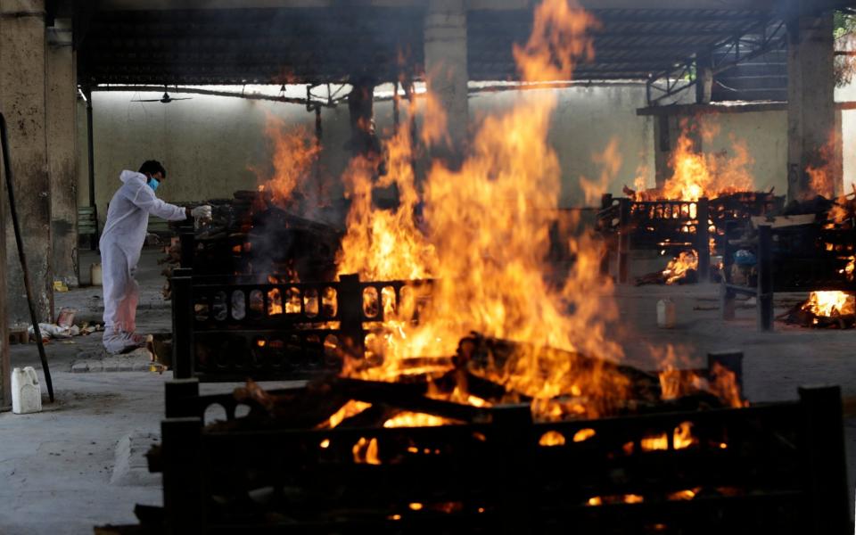 Flames rise from cremation pyres of victims of a fire that broke out in Vijay Vallabh  - Rajanish Kakade /AP