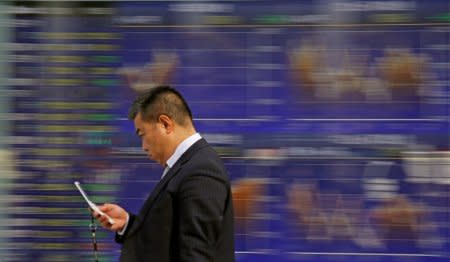 A man walks past an electronic stock quotation board outside a brokerage in Tokyo, Japan, February 9, 2018.  REUTERS/Toru Hanai