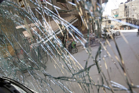 A girl on a wheelchair is seen through a shattered glass in the besieged town of Douma, Eastern Ghouta, in Damascus, Syria March 19, 2018. REUTERS/Bassam Khabieh