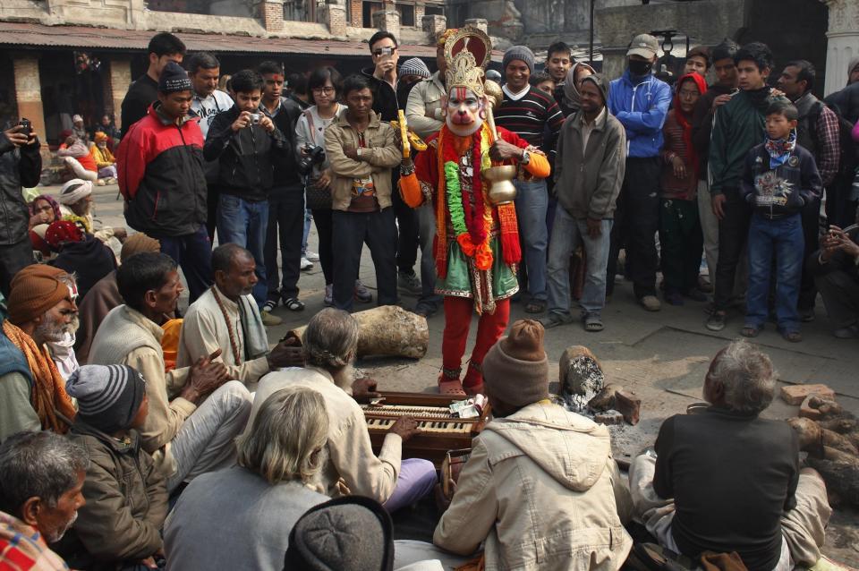 A holy man dressed as Hindu monkey god Hanuman, dances as devotees chant religious hymns in the courtyard of the Pashupatinath temple during "Shivaratri" festival in Kathmandu, Nepal, Tuesday, Feb. 17, 2015.