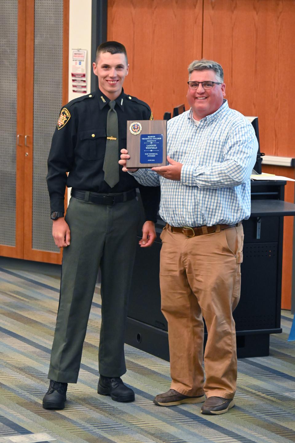 Landon Winfield received the Top Physical Fitness Award from Commander Greg Perry at the Ohio Peace Officer's Training Academy graduation in June. His father, Brandy, was a member of the second class at Marion Tech. His grandfather and uncle also served in local law enforcement.