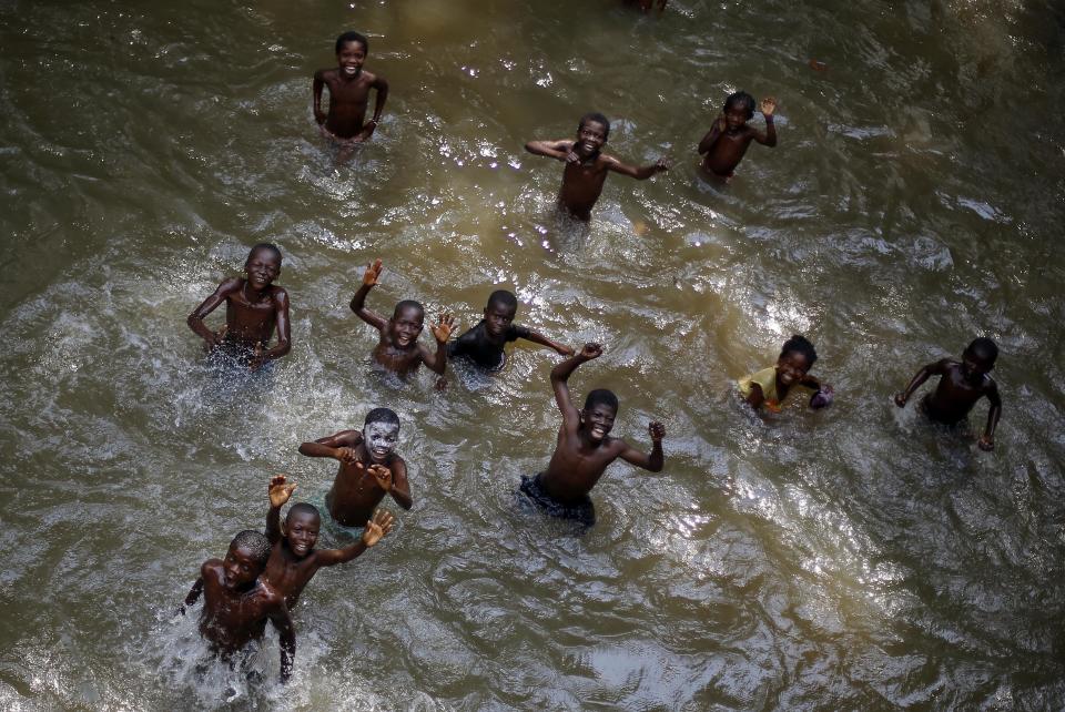 Children swimming in a river near the Central African village of Bobangui, some 50 mms (30 miles) south-west of the capital Bangui, in an area controlled by anti Balaka Christian militias, wave and smile at the photographer on Sunday Jan. 26, 2014. Thousands of African and French peacekeepers have been unable to stop mounting sectarian attacks between Christian and Muslim militias and civilians. (AP Photo/Jerome Delay)