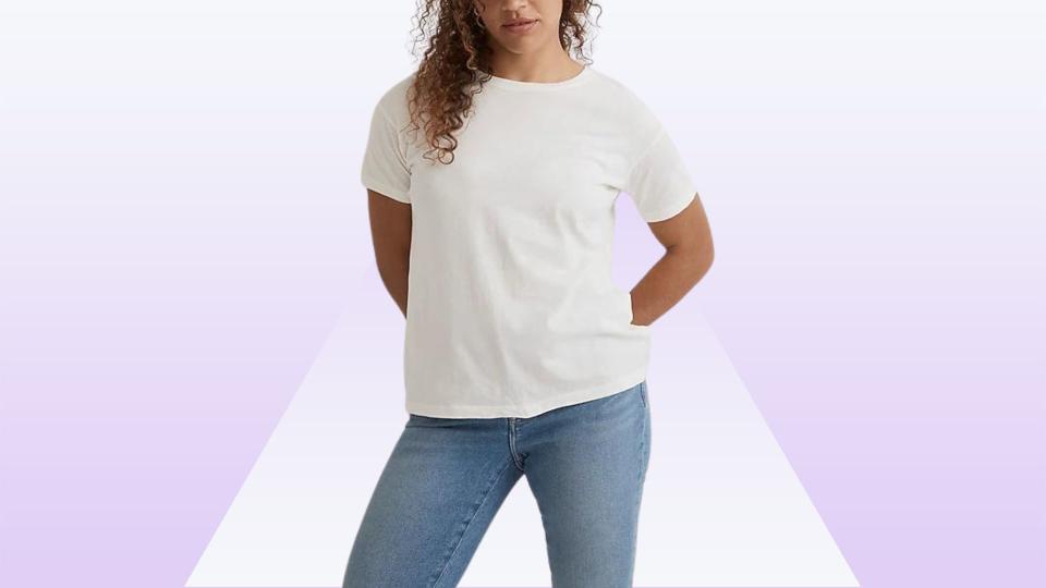 Model wearing white tee and jeans on a purple background. 