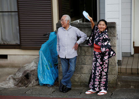 A girl fans a man as they watch the parade of a portable shrine during their Matsuri festival at Sennari district in Sakura, Chiba Prefecture, Japan, July 21, 2018. REUTERS/Kim Kyung-Hoon