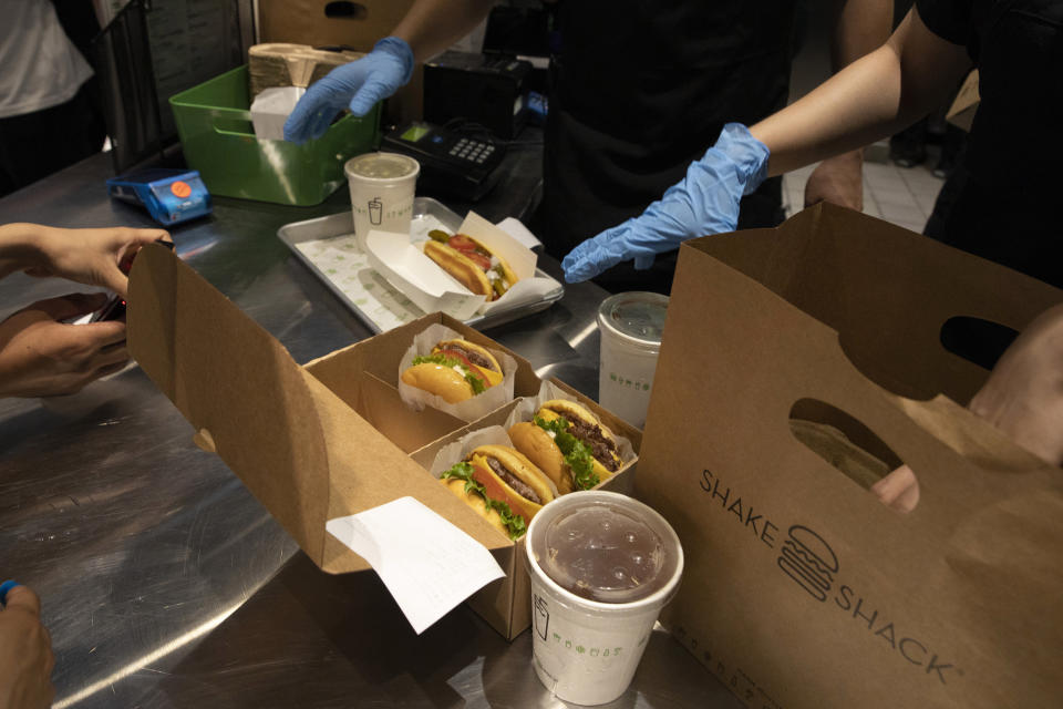 Workers prepare food at the Beijing outlet for Shake Shack in Beijing on Wednesday, Aug. 12, 2020. The U.S. headquartered burger chain is opening its first Beijing restaurant at a time when China and the U.S. are at loggerheads over a long list of issues. (AP Photo/Ng Han Guan)