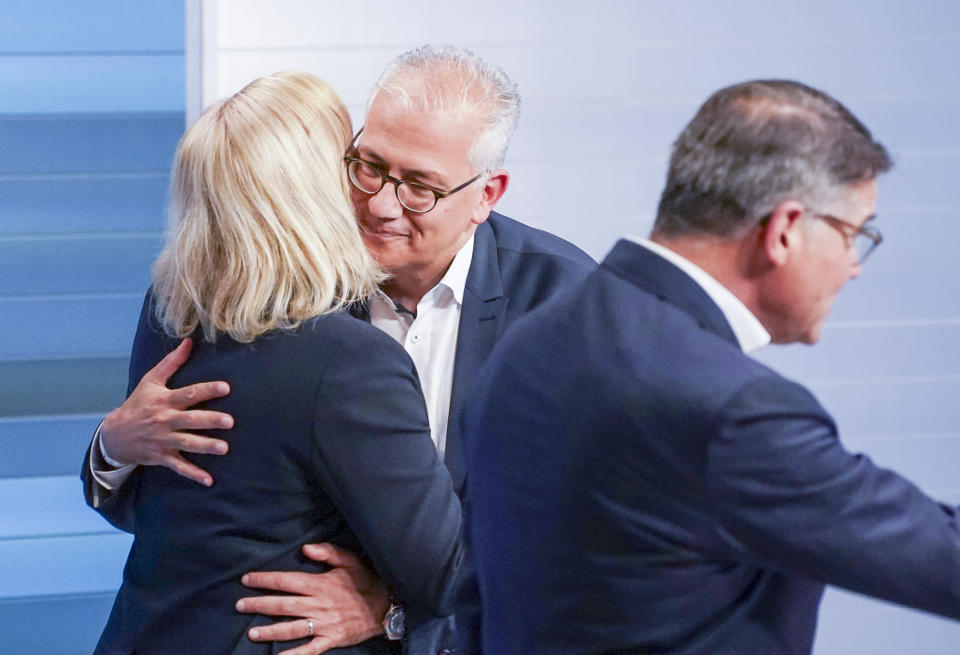Nancy Faeser, left, (SPD), top candidate and Federal Minister of the Interior, and Tarek Al-Wazir (B'ndnis 90 / Die Gr'nen), top candidate and Deputy Minister President of Hesse, embrace in the TV studio, in Wiesbaden, Germany, Sunday, Oct. 8, 2023. Boris Rhein, right, (CDU), top candidate and Minister President of Hesse, walks past them. The election for the 21st Hesse state parliament was held in Hesse on Sunday. (Andreas Arnold/dpa via AP)