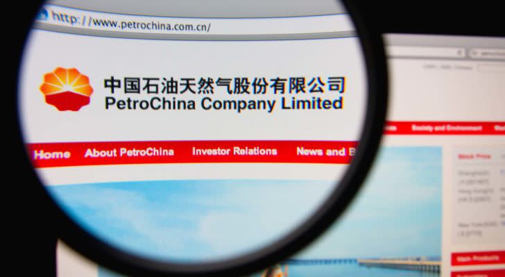 The logo for PetroChina (PTR) is displayed on the company's website viewed through a magnifying glass.