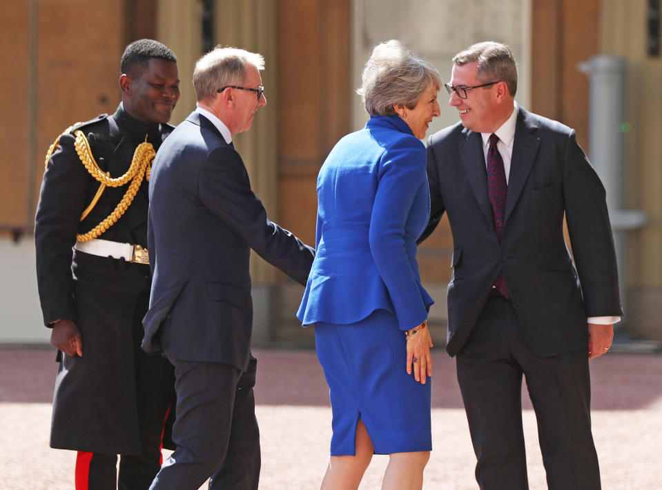 Theresa May and her husband Philip are greeted by Rt Hon Edward Young, private secretary to the Queen, and Major Nana Twumasi-Ankrah, Household Cavalry Regiment, as she arrives at Buckingham Palace in London for an audience with Queen Elizabeth II to formally resign as Prime Minister.