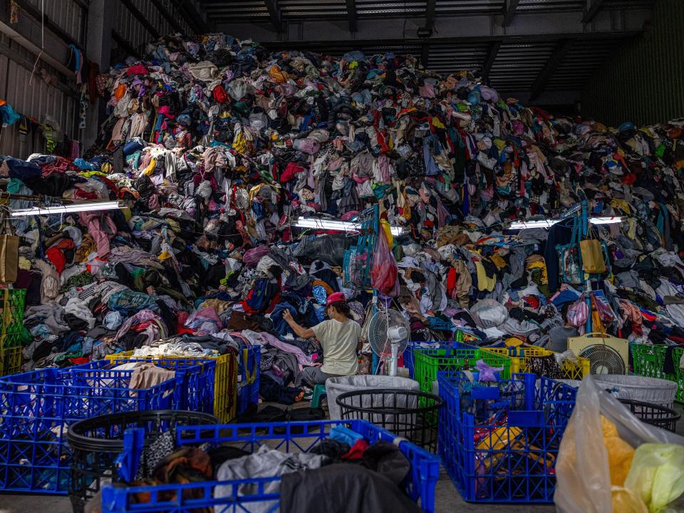 Baskets of clothes fill the room. Behind them is a mountain of unsorted clothing.