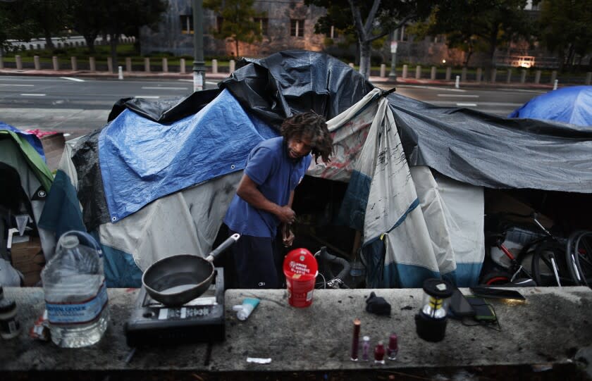 LOS ANGELES, CA - JANUARY 17, 2022: Homeless for six years, Dante Nesbit, 31, sweeps the area outside his tent at a homeless encampment on the sidewalk on Main Street January 17, 2022 in Los Angeles, California. Mayoral candidate Karen Bass wants to convert the vacant St. Vincent Medical Center near downtown into a housing facility for the homeless.(Gina Ferazzi / Los Angeles Times)