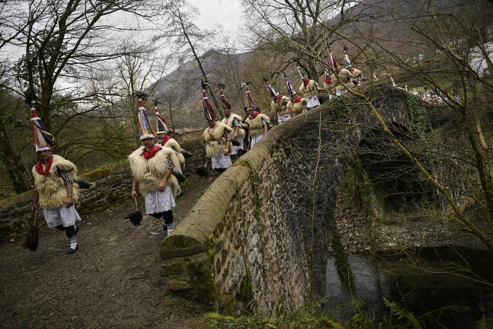 In this Monday, Jan. 27, 2020 photo, a group of ''Joaldunak'' march along the road as they take part in a Carnival in the small Pyrenee village of Ituren, northern Spain. In one of the most ancient carnival celebrations in Europe, dozens of people don sheepskins, lace petticoats and conical caps and sling cowbells across their lower backs as they parade to herald the advent of spring. (AP Photo/Alvaro Barrientos)