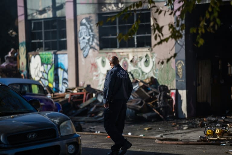 A fireman walks before a warehouse after it was destroyed by a fire, December 3, 2016 in Oakland, California