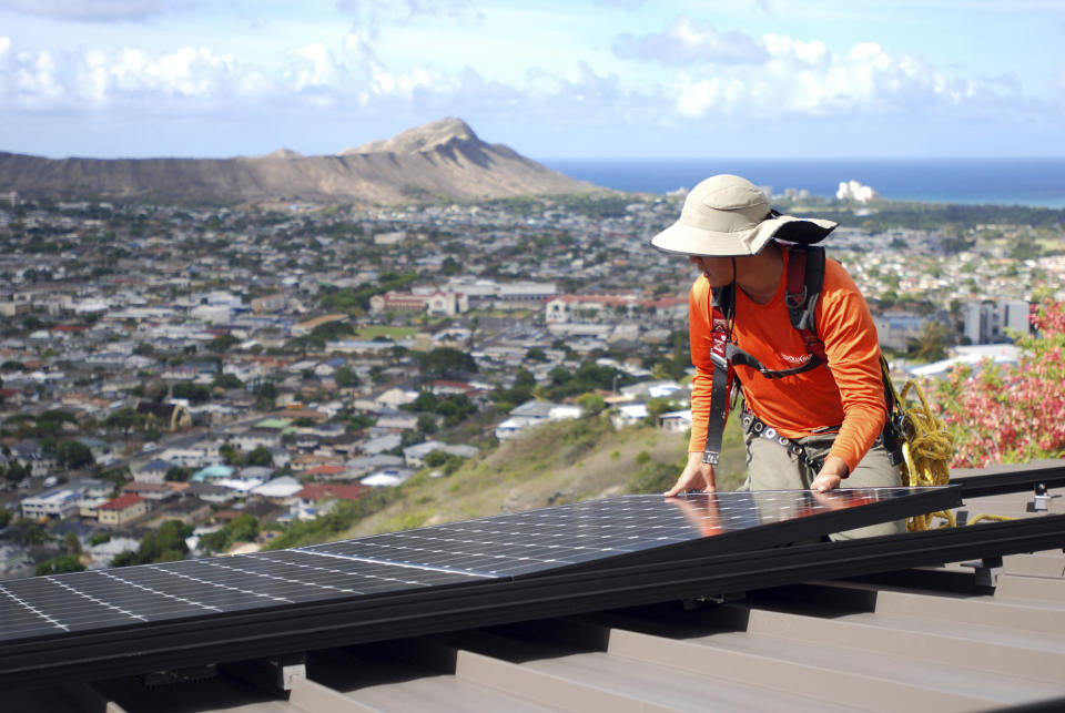 FILE - In this July 8, 2016, file photo, Dane Hew Len, lead installer for RevoluSun, places a solar panel on a roof in Honolulu. If you have the cash, most experts agree buying a solar system outright is a better investment than leasing or taking out a loan. Customers should check electric bills to estimate monthly energy use when deciding what size system to buy, and calculate federal or state incentives. (AP Photo/Cathy Bussewitz, File)