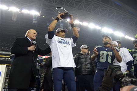 Seattle, WA, USA; Seattle Seahawks quarterback Russell Wilson hoists the George Halas Trophy after the 2013 NFC Championship football game against the San Francisco 49ers at CenturyLink Field. Mandatory Credit: Kirby Lee-USA TODAY Sports
