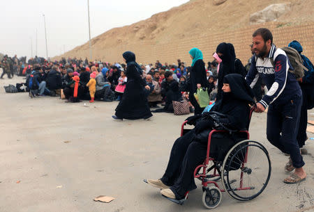 Displaced Iraqi people who have fled their homes because of the clashes, wait to be taken to safe places as Iraqi forces battle with Islamic State militants in Mosul, Iraq, March 13, 2017. REUTERS/Ari Jalal