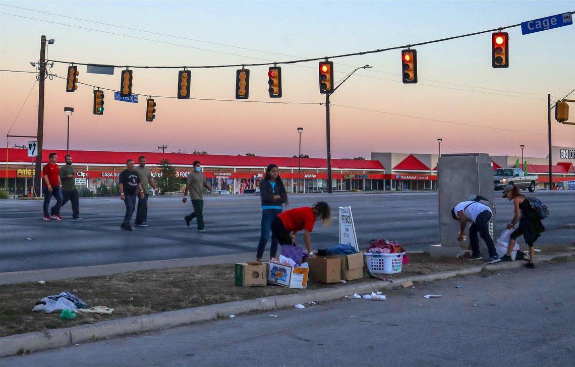 Migrants cross the street outside San Antonio’s Migrant Resource Center to look through donated boxes of clothes and momentarily escape the confines of the city’s only migrant shelter.