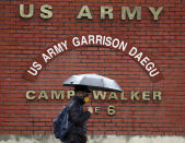 In this Tuesday, Feb. 25, 2020, photo, a man passes by U.S. Army base Camp Walker, in Daegu, South Korea. The U.S. and South Korean militaries, used to being on guard for threats from North Korea, face a new and formidable enemy that could hurt battle readiness: a virus spreading around the world that has infected more than 1,200 people in South Korea. (Kim Hyun-tae/Yonhap via AP)