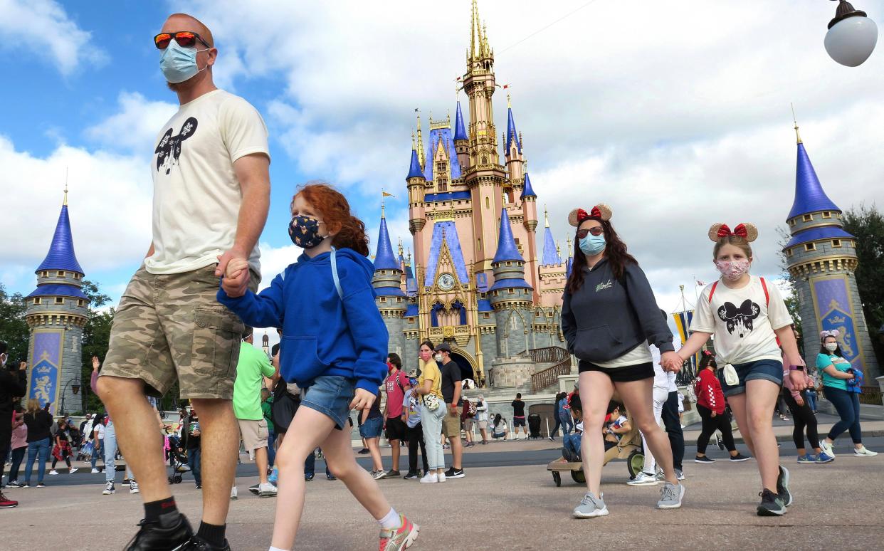 A masked family walks past Cinderella Castle in the Magic Kingdom, at Walt Disney World in Lake Buena Vista, Fla., Monday, Dec. 21, 2020. Disney's Florida parks are currently operating at 35% capacity due to the Covid-19 pandemic (AP)