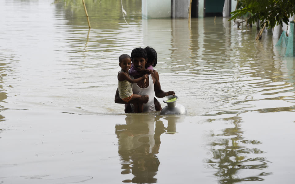 A man carries his children to a safer place in a flood-affected village of Kamrup district of Assam, India, on July 14, 2020. Villages in Assam were flooded due to heavy rains. The rising water level inundated houses, residents were forced to move to a safer place. (Photo by Hafiz Ahmed/Anadolu Agency via Getty Images)