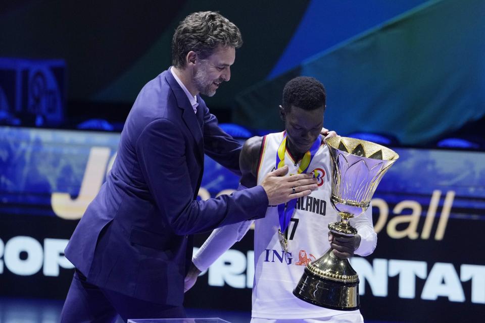 Former basketball player Pau Gasol gives a trophy to Germany guard Dennis Schroder (17) after winning the championship game of the Basketball World Cup against Serbia in Manila, Philippines, Sunday, Sept. 10, 2023. (AP Photo/Michael Conroy)