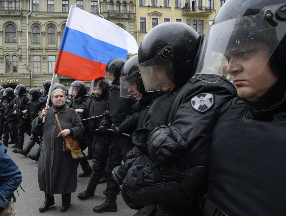 <p>A woman holding a Russian flag stands in front of riot police blocking an area during an unauthorized anti-Putin rally called by opposition leader Alexei Navalny on May 5, 2018 in Saint Petersburg, two days ahead of Vladimir Putin’s inauguration for a fourth Kremlin term. (Photo: Olga Maltseva/AFP/Getty Images) </p>