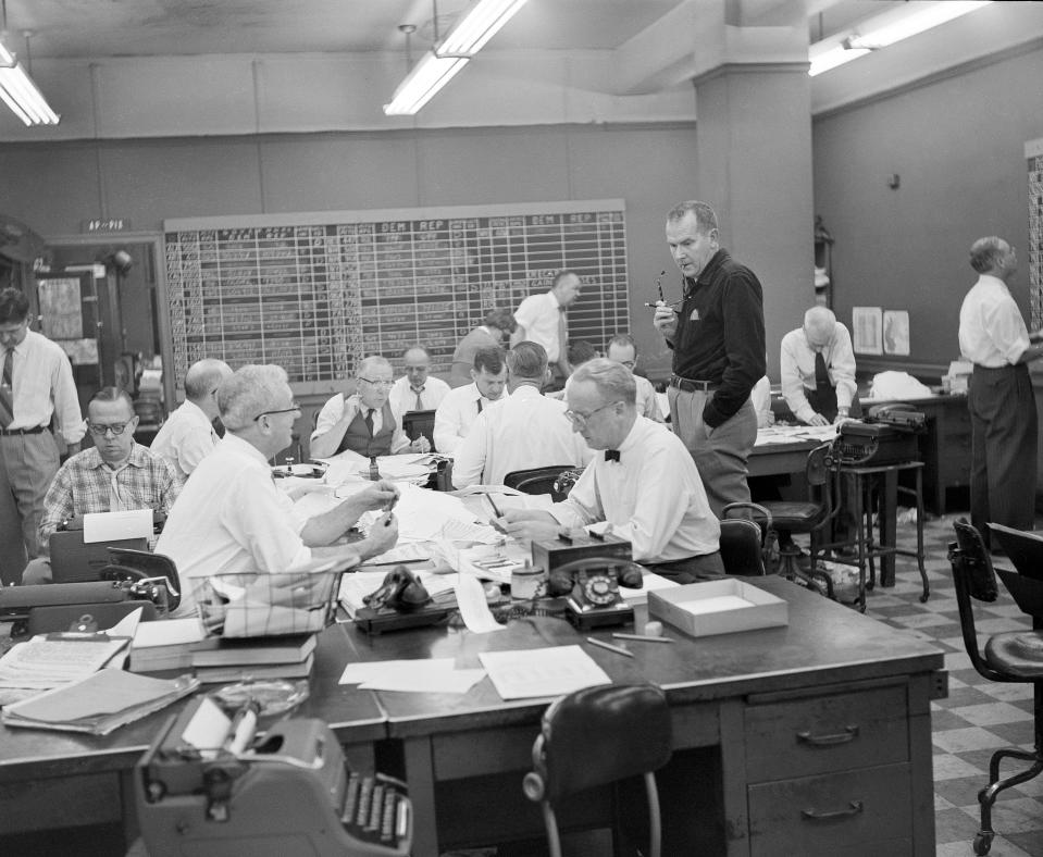 Associated Press news editor Ray Crowley, left, and chief of bureau William L. Beale, in bowtie, both in foreground, work on election night in the Washington, D.C. bureau, Nov. 4, 1958. Other identifiable staffers include: Ed Creagh at typewriter at left; Ed le Breton, standing behind Beale. (AP Photo)