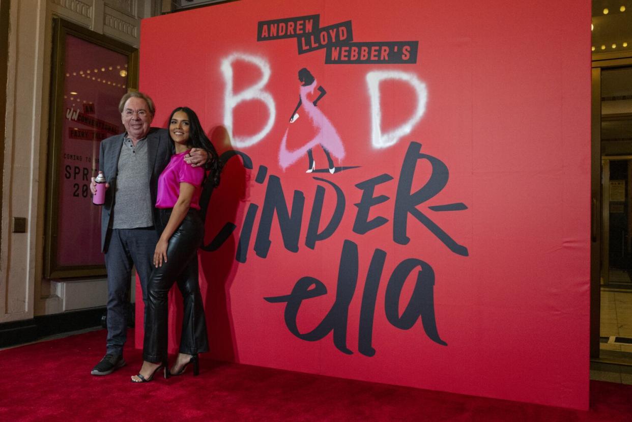 A man and woman stand on a red carpet in front of a poster-sign that says 'Bad Cinderella'