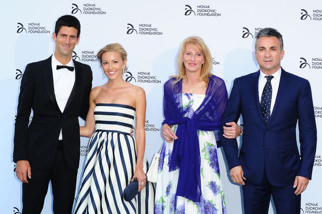 <p>Ian West/PA Images via Getty</p> Novak Djokovic and his wife, Jelena Ristic, pose alongside the tennis player's parents at the Novak Djokovic party in London.