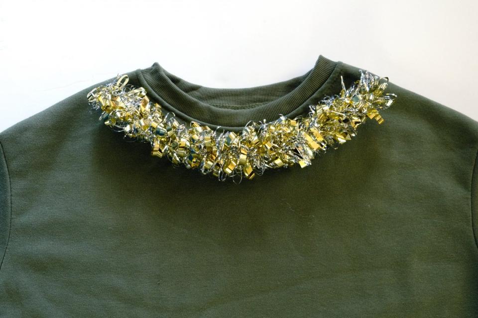 Add tinsel to collar of DIY holiday sweater.