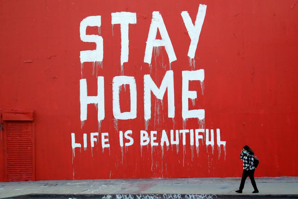 A pedestrian walks past a stay-at-home mural April 2 in Los Angeles, where schools and nonessential businesses are closed and the California governor has ordered people to stay home.  (Jose Sanchez/ASSOCIATED PRESS)