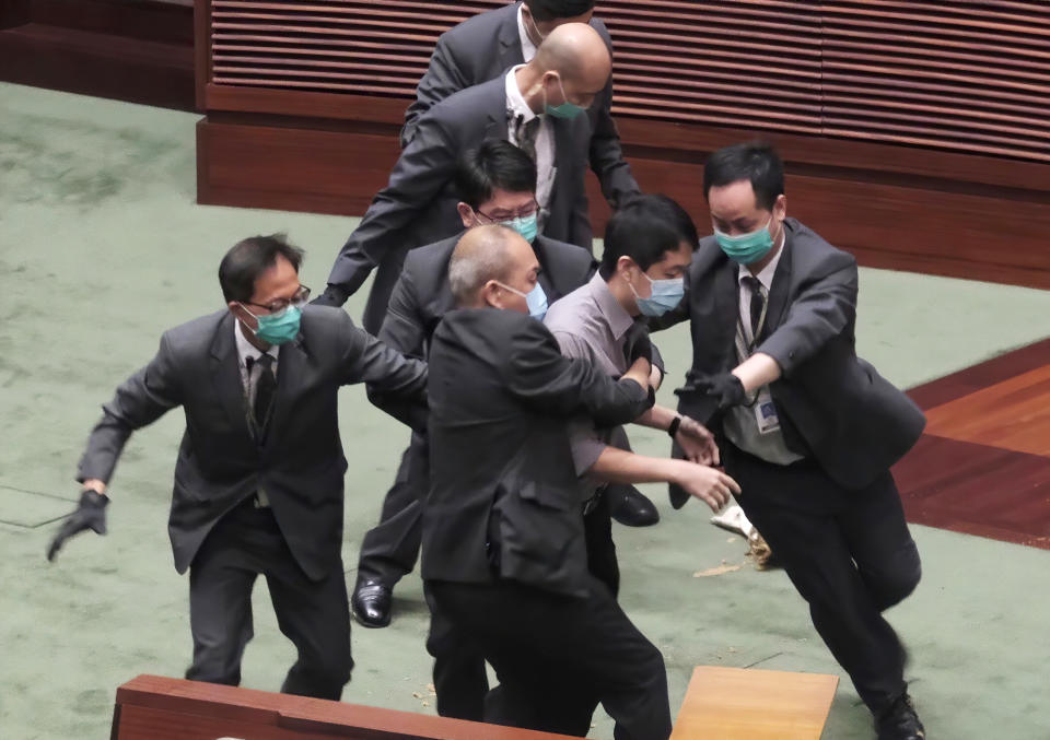 FILE - In this May 28, 2020, file photo Pro-democracy lawmaker Ted Hui, center, struggles with security personnel at the main chamber of the Legislative Council during the second day of debate on a bill that would criminalize insulting or abusing the Chinese anthem in Hong Kong. Former Hong Kong pro-democracy lawmaker and activist Ted Hui Chi-fung said, Wednesday, March 10, 2021, he had relocated to Australia where he would continue campaigning against the Chinese Communist Party. (AP Photo, FILE)