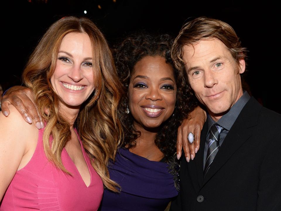 Julia Roberts, in a pink dress, smiles while posing with Oprah Winfrey (in the center), and Danny Moder (Roberts' husband) in this photo from the 2014 Screen Actors' Guild awards.