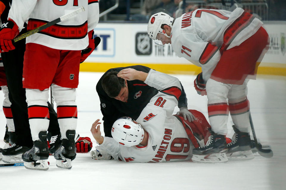 COLUMBUS, OH - JANUARY 16:  Dougie Hamilton #19 of the Carolina Hurricanes is checked on by head athletic trainer Doug Bennett after getting injured during the second period against the Columbus Blue Jackets on January 16, 2020 at Nationwide Arena in Columbus, Ohio. (Photo by Kirk Irwin/Getty Images)