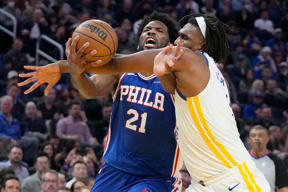 Philadelphia 76ers center Joel Embiid (21) is fouled by Golden State Warriors forward Kevon Looney while driving to the basket during the first half of an NBA basketball game in San Francisco, Friday, March 24, 2023. (AP Photo/Jeff Chiu)