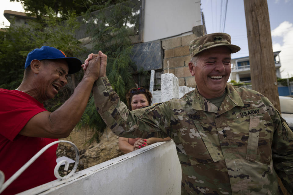 A National Guardsman greets a neighbor after delivering water to the residents of Punta Diamante in Ponce, Puerto Rico, Wednesday, September 21, 2022. (AP Photo/Alejandro Granadillo)