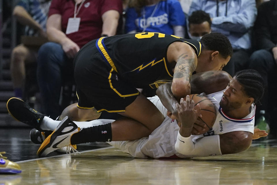 Golden State Warriors forward Juan Toscano-Anderson, top, and Los Angeles Clippers guard Paul George (13) battle for the ball during the first half of an NBA basketball game in Los Angeles, Sunday, Nov. 28, 2021. (AP Photo/Ashley Landis)