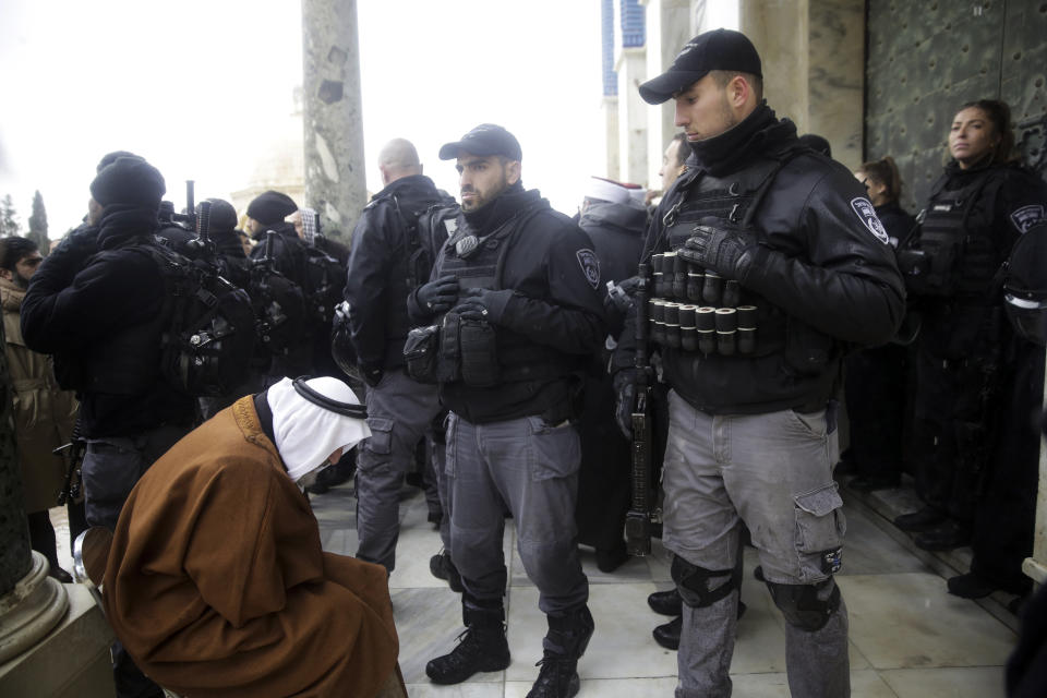 Israeli police stands at the door to the Dome of the Rock mosque confronted by Palestinians, Monday, Jan. 14, 2019. Scuffles broke out at the Dome of the Rock in Jerusalem's Old City on Monday after guards at the mosque refused to allow an Israeli policeman to enter for a routine security check because he was wearing a Jewish skullcap known as a kippah. (AP Photo/Mahmoud Illean)