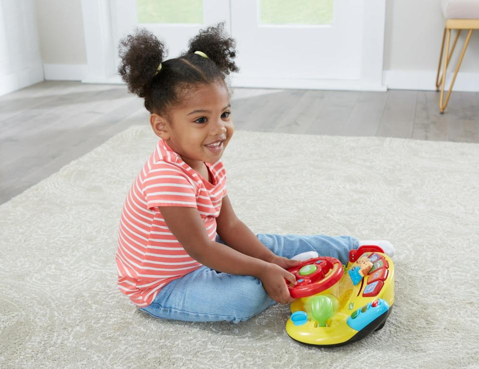 girl playing with toy steering column