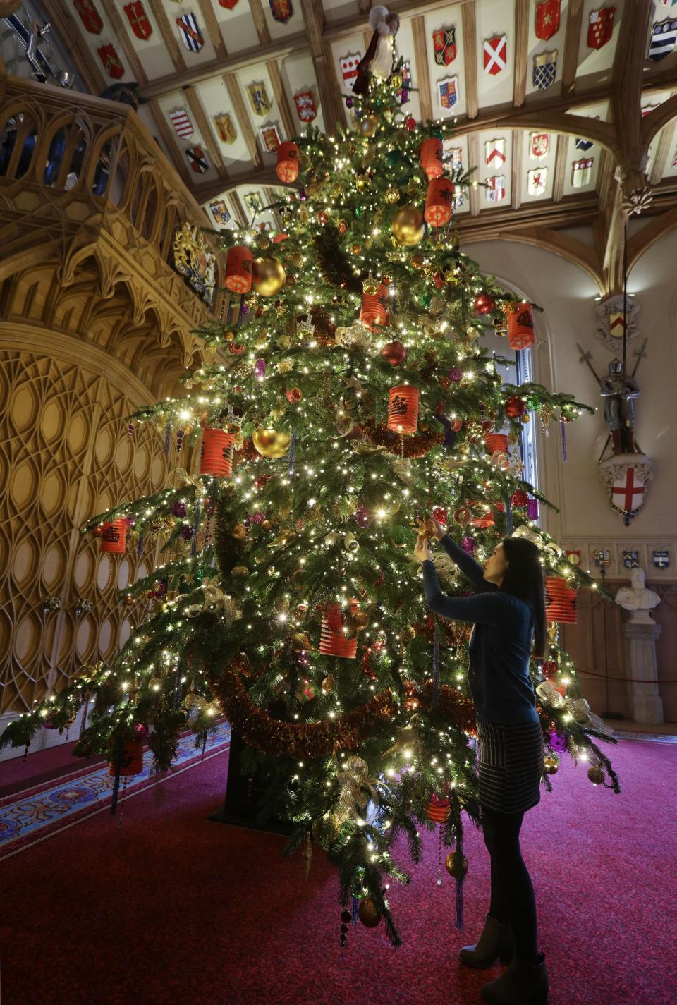 A Royal Collection Trust staff member puts the finishing touches to a 20ft Nordmann fir tree in St George's Hall, as part of Christmas decorations being put up at Windsor Castle, Berkshire. (Photo by Yui Mok/PA Images via Getty Images)