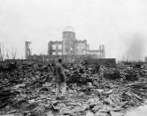 FILE - In this Sept. 8, 1945, file photo, an allied correspondent stands in a sea of rubble before the shell of a building that once was a movie theater in Hiroshima, western Japan, a month after the first atomic bomb ever used in warfare was dropped by the U.S. to hasten Japan's surrender. Many people exposed to radiation developed symptoms such as vomiting and hair loss. Most of those with severe radiation symptoms died within three to six weeks. Others who lived beyond that developed health problems related to burns and radiation-induced cancers and other illnesses. (AP Photo/Stanley Troutman, Pool, File)