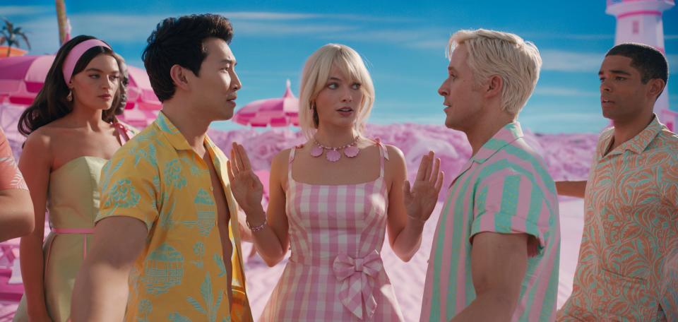 Barbie (Margot Robbie, center) is the center of attention for rival Kens (Simu Liu and Ryan Gosling) in "Barbie."