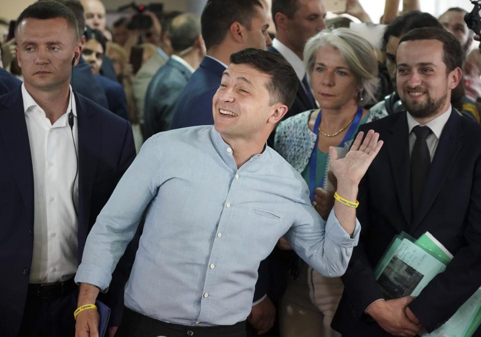 Ukrainian President Volodymyr Zelenskiy, center, gestures as he arrives at a polling station during a parliamentary election in Kiev, Ukraine, Sunday, July 21, 2019. Ukrainians are voting in an early parliamentary election in which the new party of President Volodymyr Zelenskiy is set to take the largest share of votes. (AP Photo/Evgeniy Maloletka)