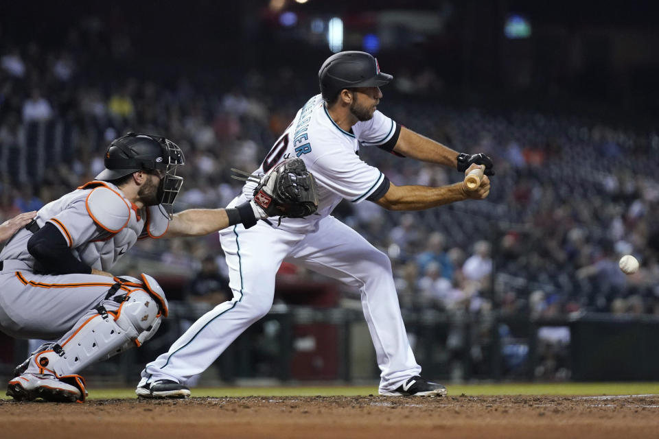 Arizona Diamondbacks' Madison Bumgarner, right, drops down a sacrifice bunt next to San Francisco Giants catcher Curt Casali during the fourth inning of a baseball game, Tuesday, Aug. 3, 2021, in Phoenix. (AP Photo/Ross D. Franklin)