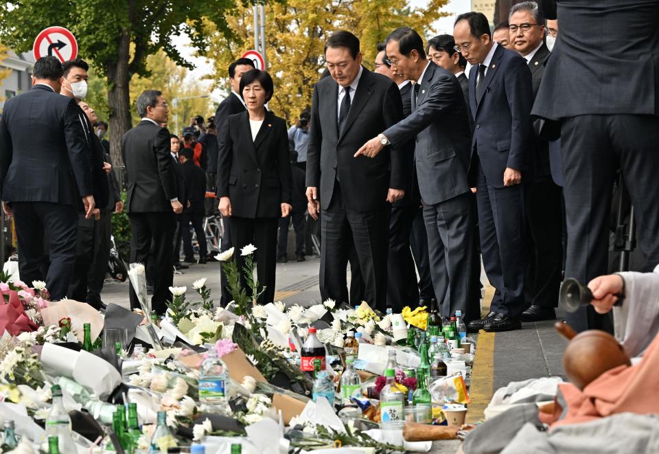 South Korean president Yoon Suk-yeol speaks with prime minister Han Duck-soo (centre R) as they visit a makeshift memorial for the victims of the deadly Halloween crowd surge, outside a subway station in the district of Itaewon in Seoul on 1 November 2022 (AFP via Getty Images)