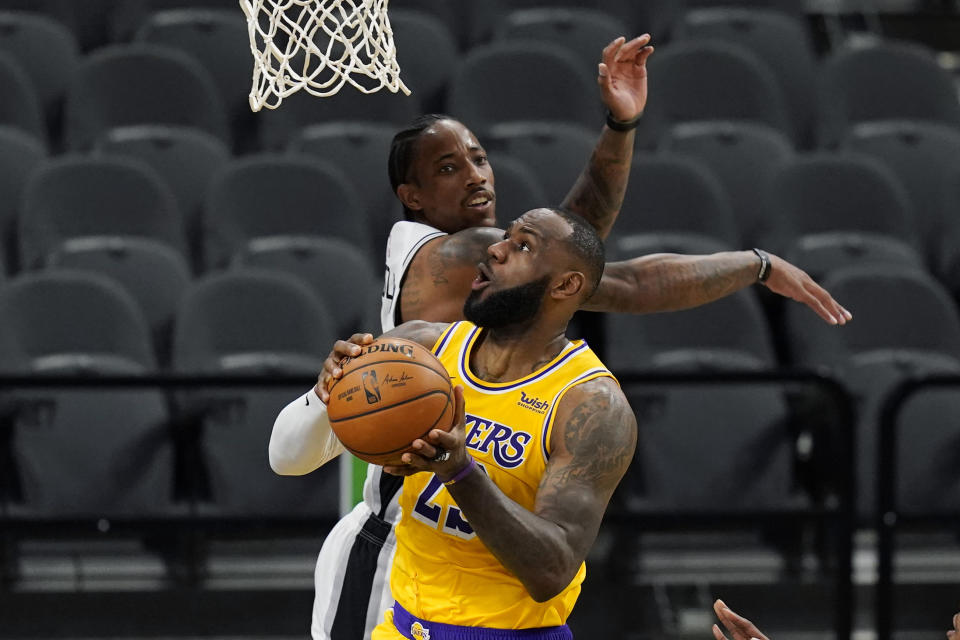 Los Angeles Lakers forward LeBron James (23) scores past San Antonio Spurs guard DeMar DeRozan during the first half of an NBA basketball game in San Antonio, Wednesday, Dec. 30, 2020. (AP Photo/Eric Gay)