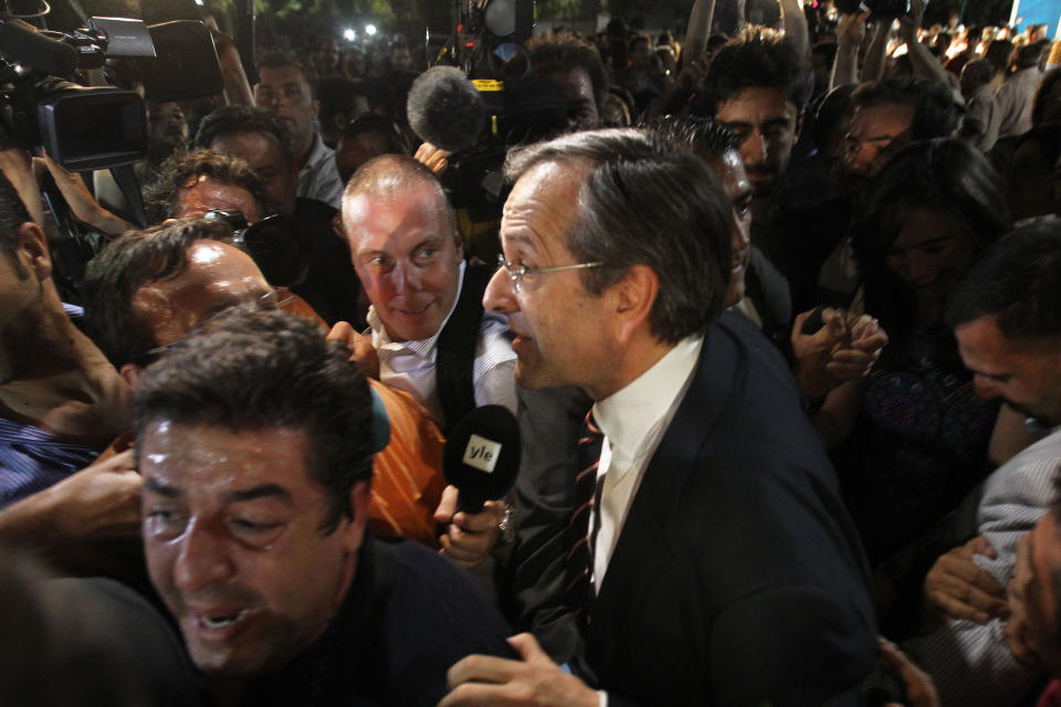 Leader of the New Democracy conservative party Antonis Samaras surrounded by media, leaves an elections kiosk after speaking to his supporters at Syntagma square in Athens, late Sunday, June 17, 2012. The pro-bailout New Democracy party came in first Sunday in Greece's national election, and its leader has proposed forming a pro-euro coalition government. (AP Photo/Petros Karadjias)